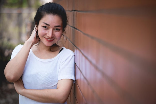 Portrait d'une belle fille asiatique chic pose pour prendre une photo sur un mur de briques