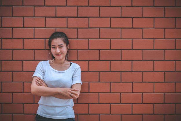 Portrait d'une belle fille asiatique chic pose pour prendre une photo sur un mur de briques