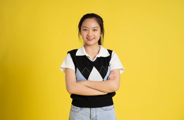 Portrait d'une belle fille asiatique posant sur fond jaune