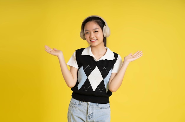 Portrait d'une belle fille asiatique posant sur fond jaune