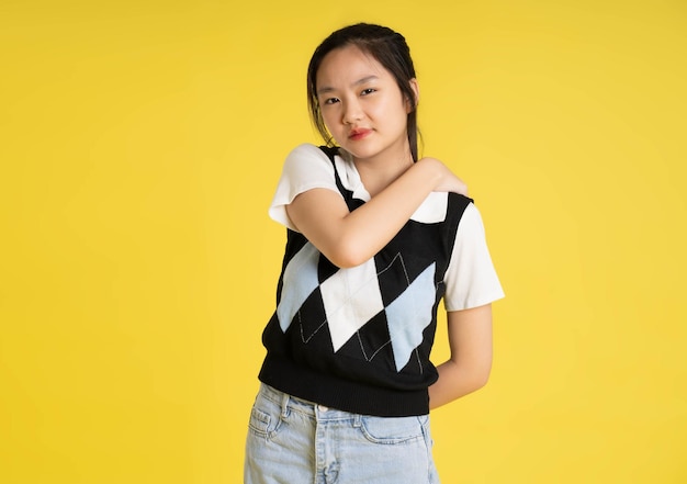 Portrait d'une belle fille asiatique posant sur fond jaune