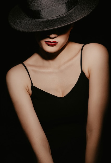 Portrait d'une belle fille au chapeau noir et robe