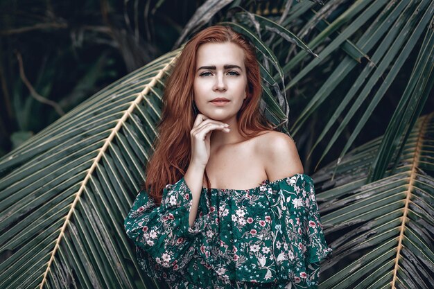 portrait d'une belle fille aux cheveux rouges sur fond de palmier