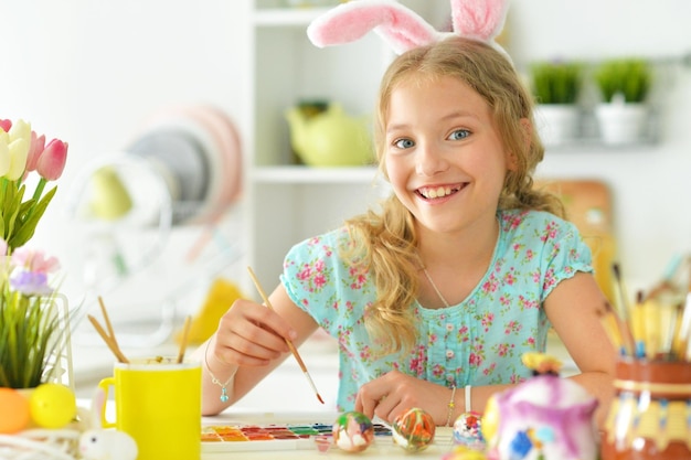 Portrait d'une belle fille aux oreilles de lapin peignant des oeufs pour les vacances de Pâques