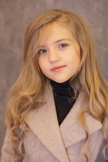 portrait d'une belle fille blonde aux cheveux longs dans un manteau et un chemisier noir