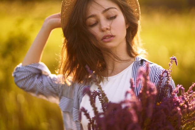 Portrait d'une belle fille avec un bouquet de lavande. Coucher de soleil léger et belle sensualité. La fille profite du moment