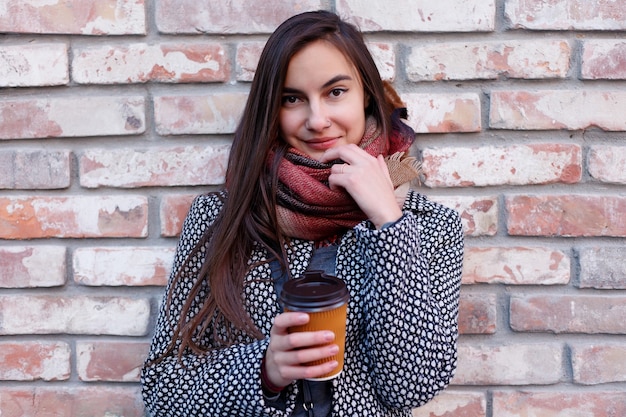 Portrait de la belle fille brune avec boisson à emporter dans la rue