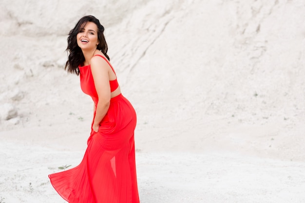 Portrait d'une belle fille brune souriante et vêtue d'une robe rouge