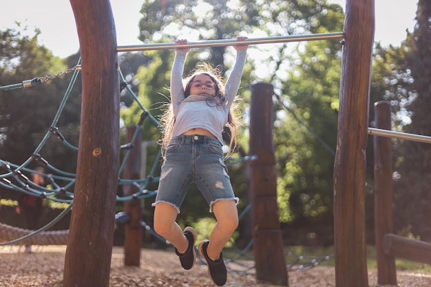 Portrait d'une belle fille caucasienne fait des pompes sur la barre horizontale dans le terrain de jeu