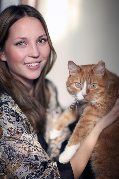 Photo portrait d'une belle fille avec un chat rouge