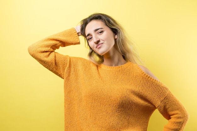 Le portrait d'une belle fille dans un chandail orange regarde de côté avec une expression pensive