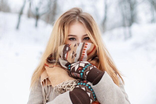 Portrait d'une belle fille dans une écharpe et des gants dans le parc d'hiver