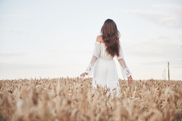 Portrait d'une belle fille dans une robe blanche dans le champ de blé