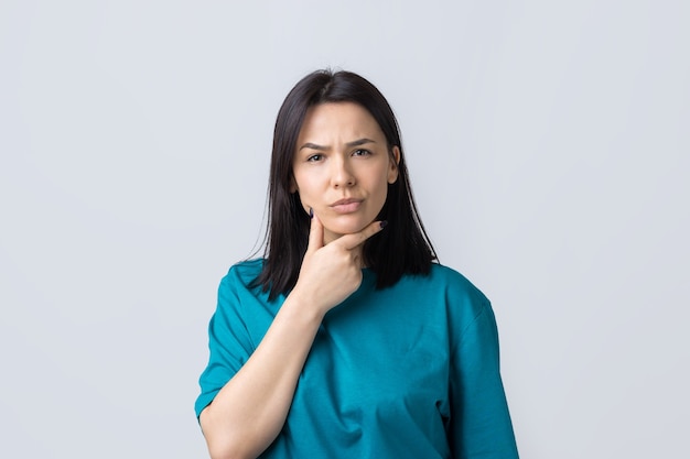 Le portrait d'une belle fille dans un t-shirt bleu regarde de côté avec une expression pensive