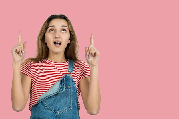 Le portrait d'une belle fille dans un t-shirt rayé regarde de côté avec une expression pensive envisage un plan d'action supplémentaire