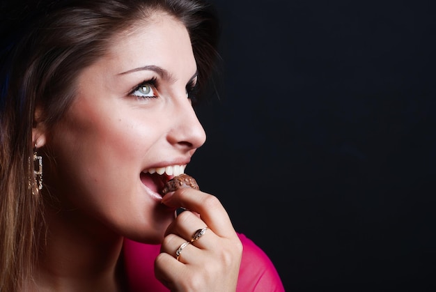 Portrait de belle fille dans une veste de femme rose avec un bonbon au chocolat dans la bouche