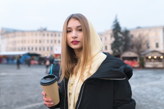 Portrait d'une belle fille dans une veste avec une tasse de café dans les mains