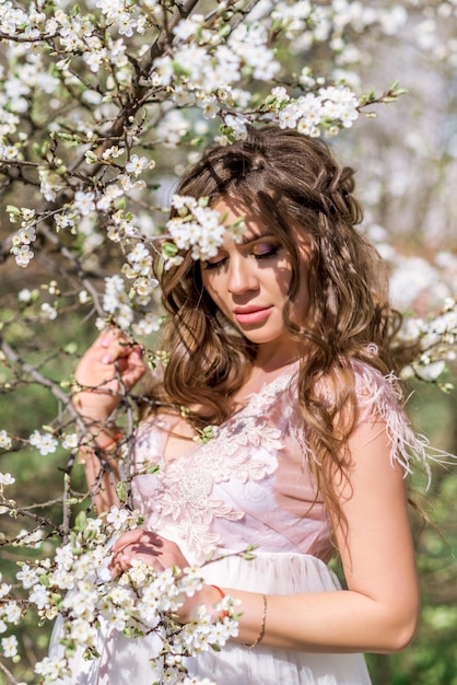 Portrait d'une belle fille enceinte dans le jardin de printemps