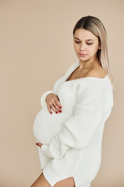 Un portrait de la belle fille enceinte vêtue d'un pull blanc