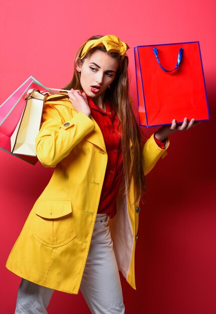 Portrait d'une belle fille excitée tenant des sacs à provisions sur fond rouge femme appréciant le shopping elle porte des sacs à provisions femme shopper femme joyeuse tenant un cadeau