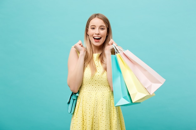 Portrait d&#39;une belle fille excitée vêtue d&#39;une robe jaune tenant des sacs à provisions