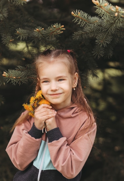 Portrait d'une belle fille avec des fleurs dans ses mains dans le parc en été. La fille aime passer du temps seule. Verticale