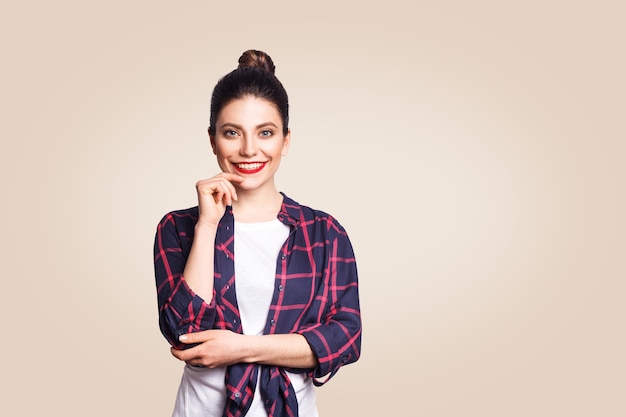 Portrait de belle fille heureuse dans un style décontracté en regardant la caméra avec un sourire à pleines dents. tourné en studio sur fond beige.