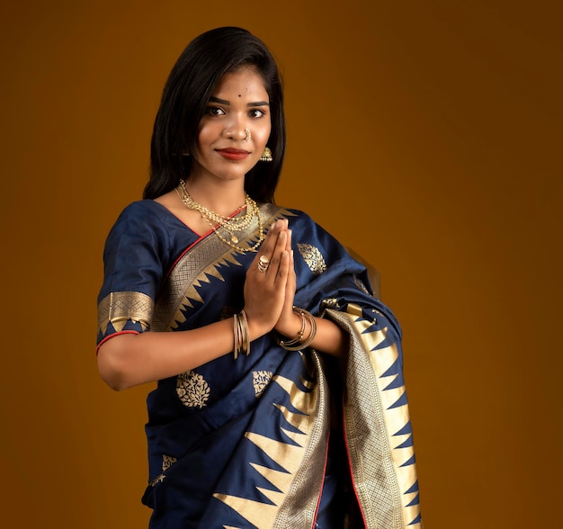 Portrait d'une belle fille indienne dans une pose de salutation aux mains de Namaste. Femme indienne en sari traditionnel.