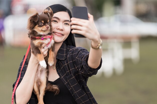 Photo portrait d'une belle fille jouant avec son adorable chiot à l'extérieur dans le parc public. un petit chien avec son propriétaire passe une journée au parc à jouer et à s'amuser. amour pour animaux de compagnie photo