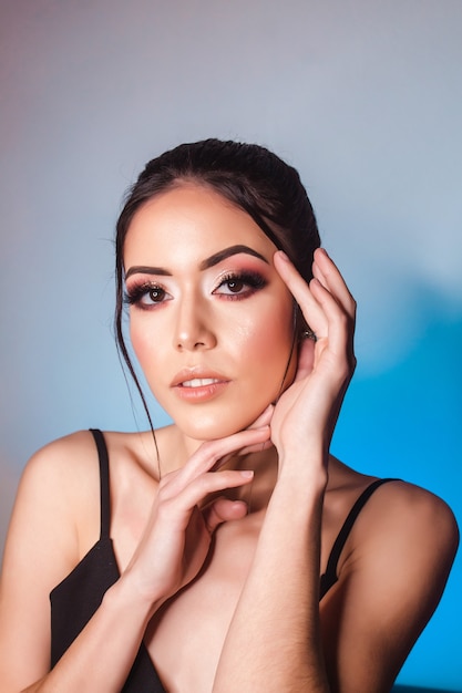 Portrait d'une belle fille avec un maquillage artistique et des lumières bleu clair en arrière-plan.