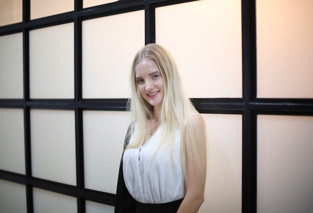 Portrait d'une belle fille de mode aux cheveux blonds posé à l'intérieur.