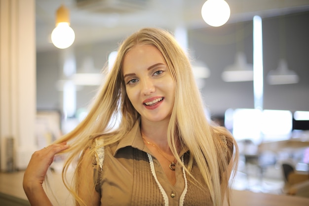 Portrait d'une belle fille de mode aux cheveux blonds posé à l'intérieur.