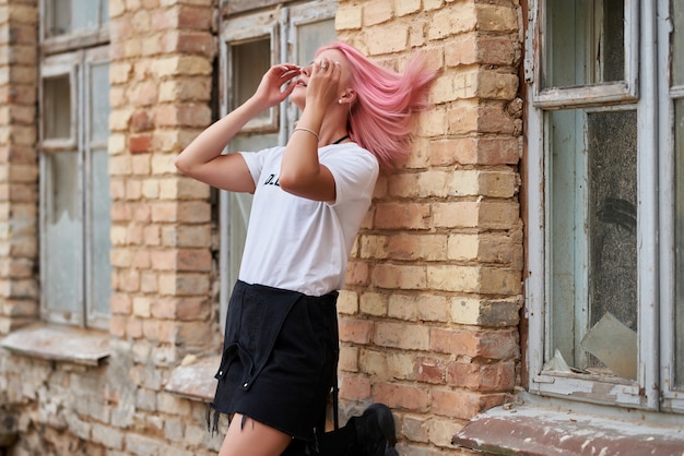 Portrait d'une belle fille posant contre un mur de briques