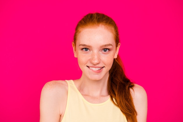 Portrait belle fille rousse isolée sur mur rose