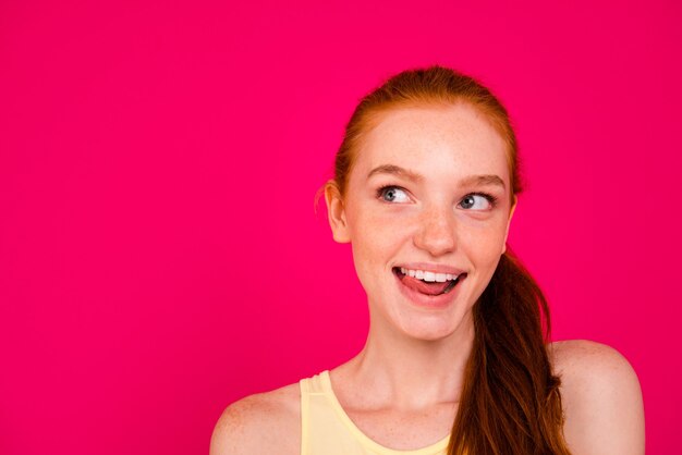 Portrait belle fille rousse isolée sur mur rose