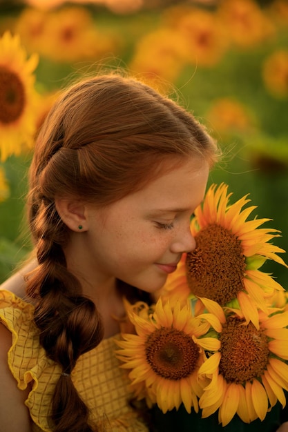 Portrait d'une belle fille rousse avec des nattes avec un bouquet de tournesols dans ses mains l'été dans le village un champ de tournesols