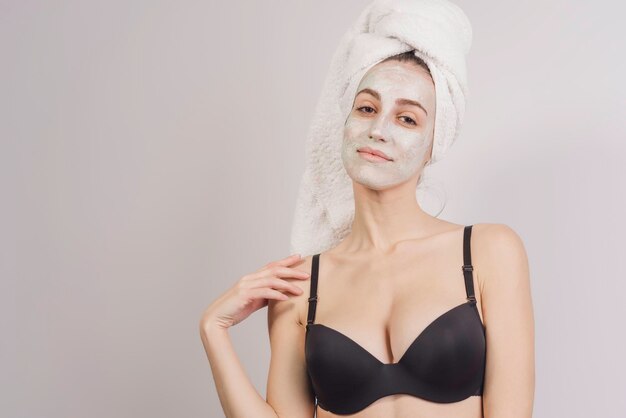 Photo portrait d'une belle fille avec une serviette sur la tête et un masque facial, relaxant à la maison