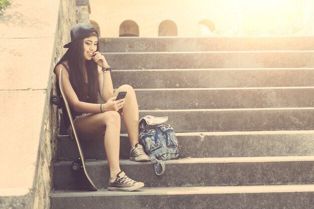 Portrait d&#39;une belle fille de skateur en regardant un téléphone intelligent