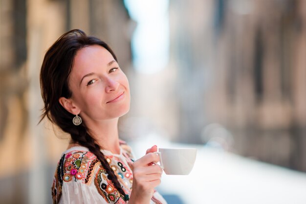 Portrait De Belle Fille Avec Une Tasse De Café Dans La Rue. Caucasien Touristique Profiter De Ses Vacances En Europe Dans La Ville Vide