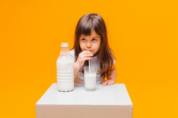 Portrait de belle fille avec un verre de lait sur fond jaune