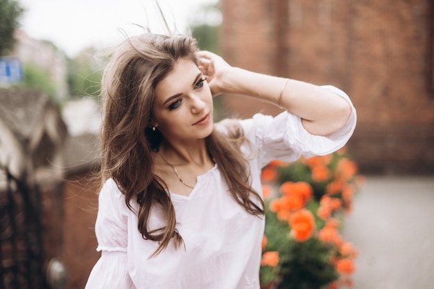 Portrait d&#39;une belle fille vêtue de blanc et debout près des fleurs