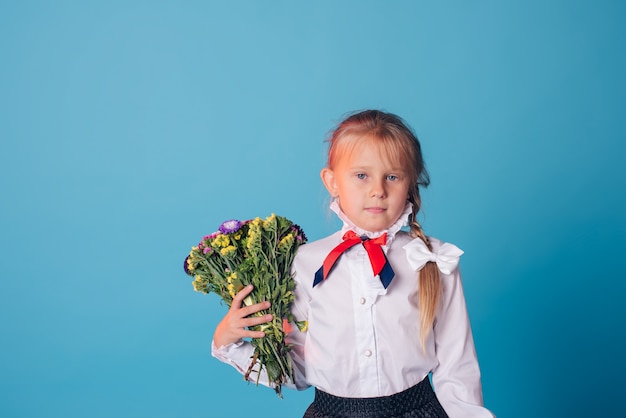 Portrait de la belle jeune élève de première année. Fille de première année dans le studio avec des fleurs