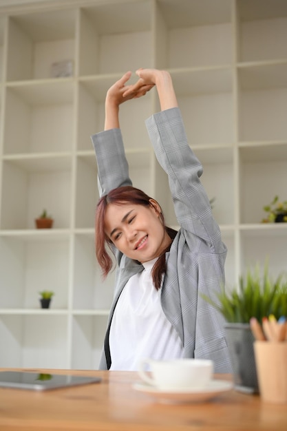 Portrait d'une belle jeune femme d'affaires asiatique étirant ses bras et se relaxant au travail