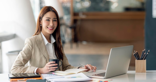 Portrait d'une belle jeune femme d'affaires souriante travaillant au bureau en souriant et en regardant la caméra