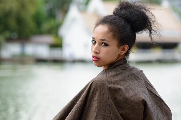 Portrait de la belle jeune femme africaine aux cheveux afro se détendre dans le parc en plein air