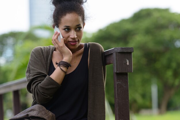 Portrait de la belle jeune femme africaine aux cheveux afro se détendre dans le parc en plein air