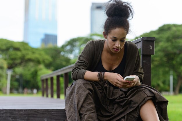 Portrait de la belle jeune femme africaine aux cheveux afro se détendre dans le parc en plein air