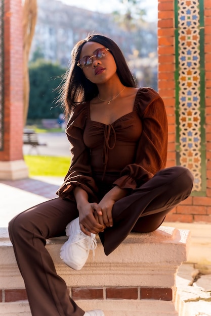 Portrait d'une belle jeune femme africaine naturelle souriante assise dans un parc à l'extérieur au coucher du soleil