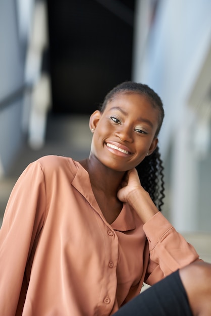 Portrait d'une belle jeune femme afro-américaine debout contre des escaliers dans un bâtiment