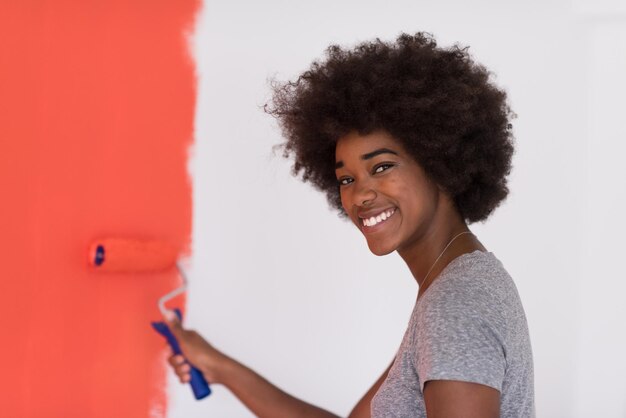 portrait d'une belle jeune femme afro-américaine peignant un mur dans son nouvel appartement